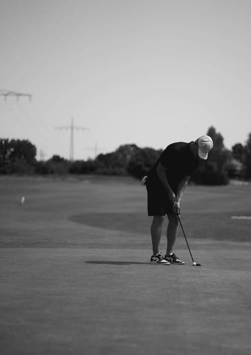 Schwarz-Weiß-Aufnahme von Tim Stützle auf dem Golfplatz, im Hintergrund Strommasten